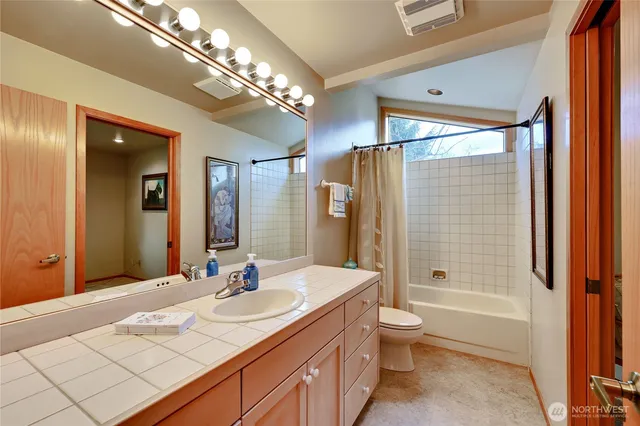 a bathroom with a granite countertop sink a toilet a mirror and shower