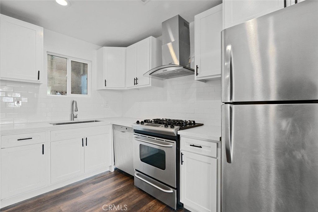 a kitchen with stainless steel appliances wooden floor sink and stove