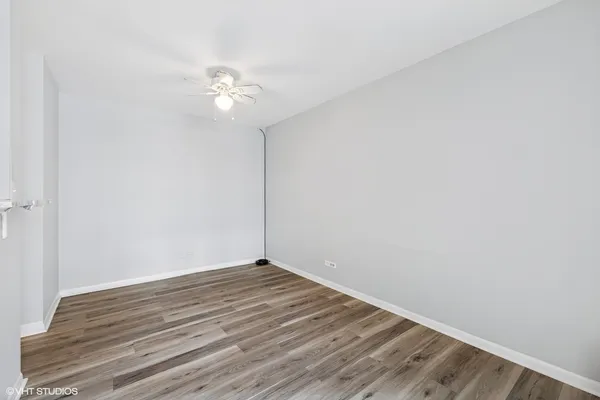 an empty room with wooden floor and fan