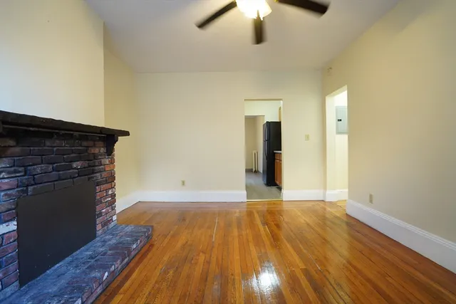 a view of empty room with wooden floor and fireplace