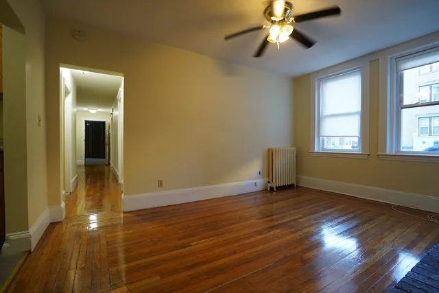 a view of an empty room with window and wooden floor