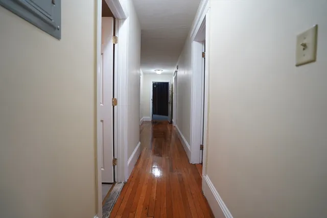 a view of a hallway with wooden floor and a bathroom