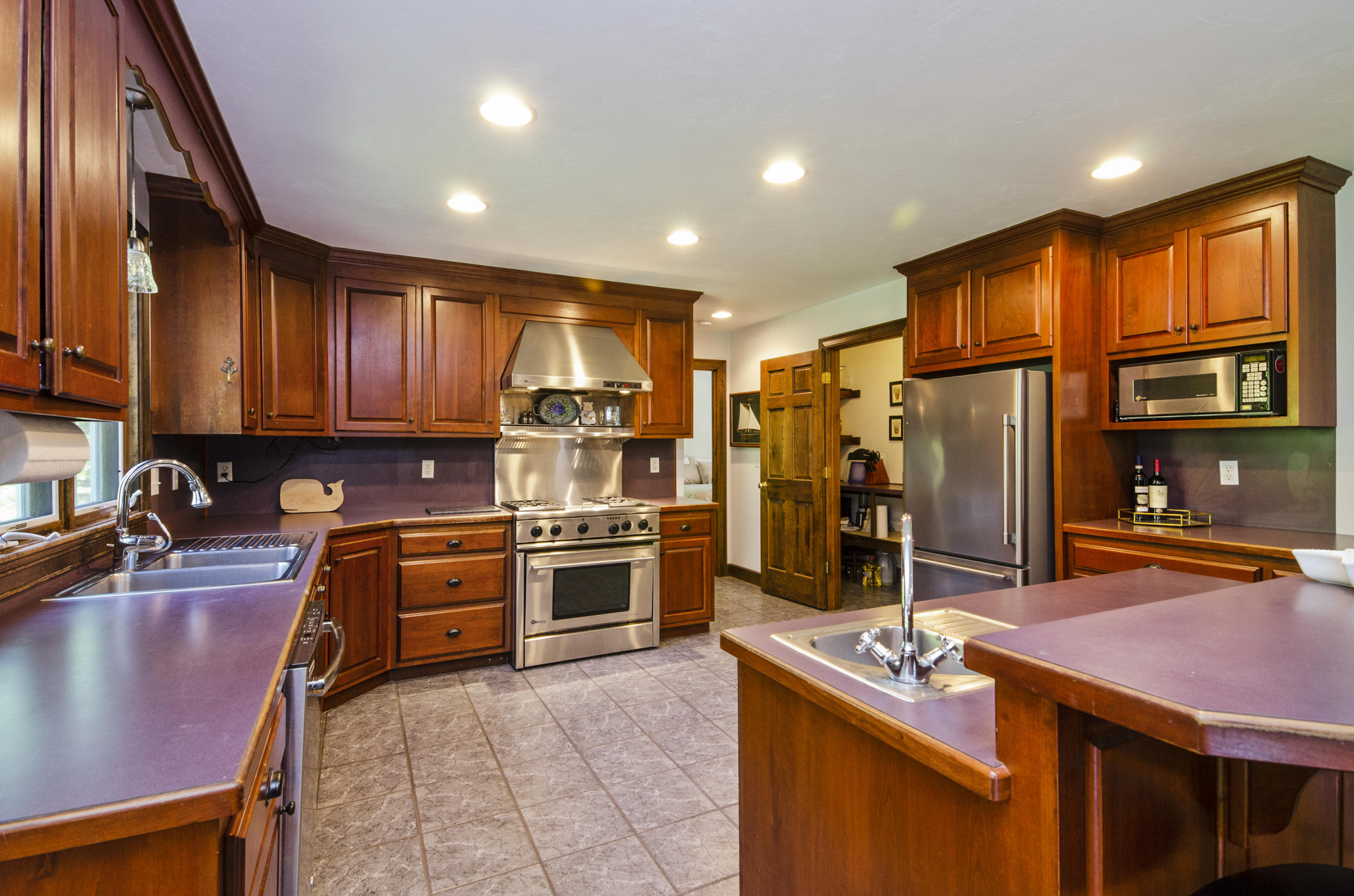 50 Waterhouse Road Bourne, MA 02532 - Photo 9 of 25 a kitchen with stainless steel appliances granite countertop a stove top oven a sink dishwasher a dining table and chairs with wooden floor