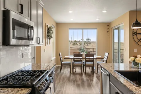 a kitchen with stainless steel appliances granite countertop a stove a sink dishwasher a dining table and chairs with wooden floor