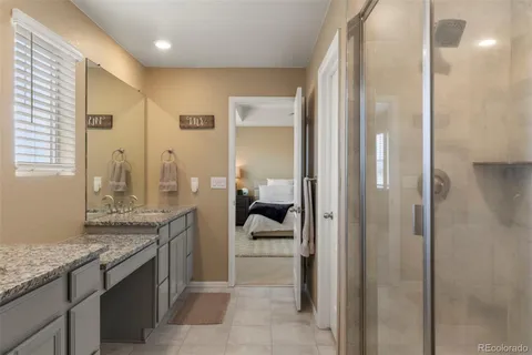 a bathroom with a granite countertop sink a mirror and a shower