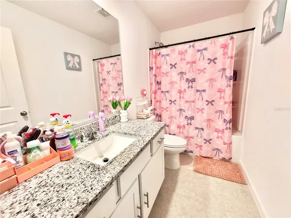 a bathroom with a granite countertop sink a vanity and a shower curtain
