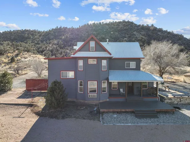a front view of a house with a yard and mountain view in back