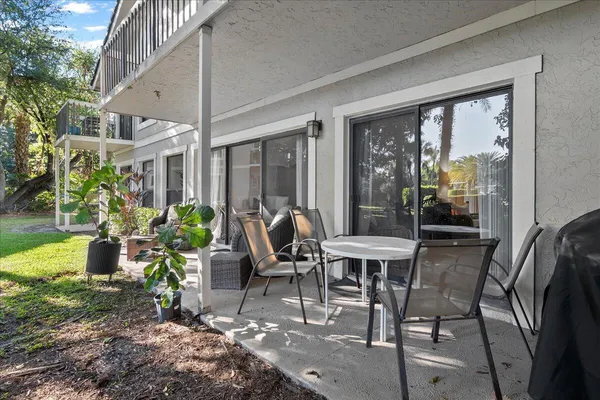 a view of a patio with table and chairs potted plants with floor to ceiling window and potted plants