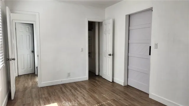 an empty room with wooden floor & closet area