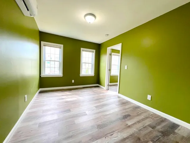 a view of an empty room with window and wooden floor