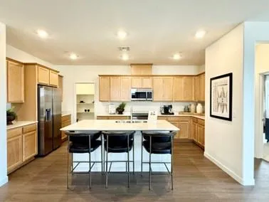 a kitchen with stainless steel appliances a dining table chairs refrigerator sink and cabinets