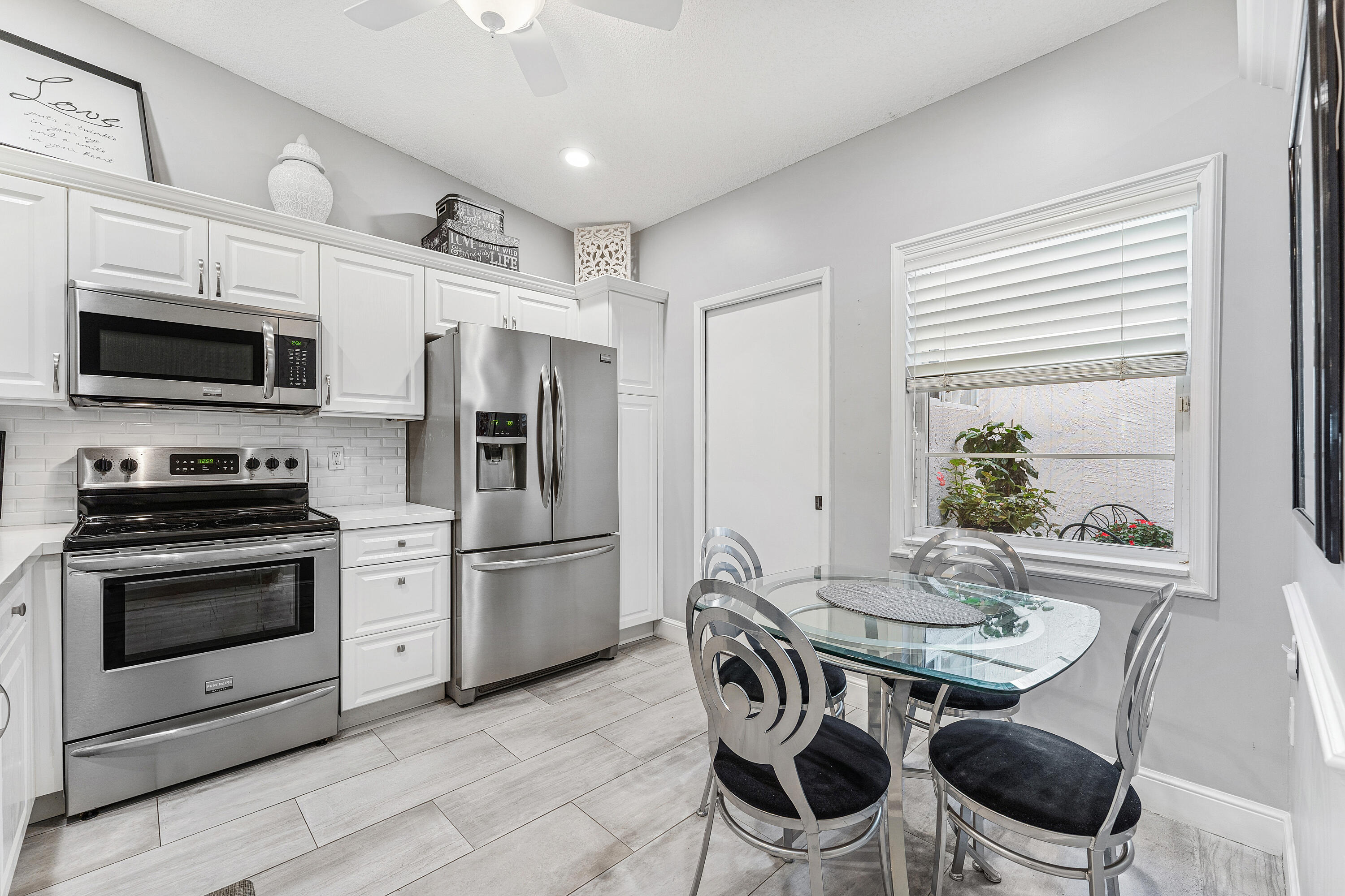 6348 Pointe Pleasant Circle Delray Beach, FL 33484 - Photo 7 of 40 a kitchen with stainless steel appliances a stove a microwave a dining table and chairs