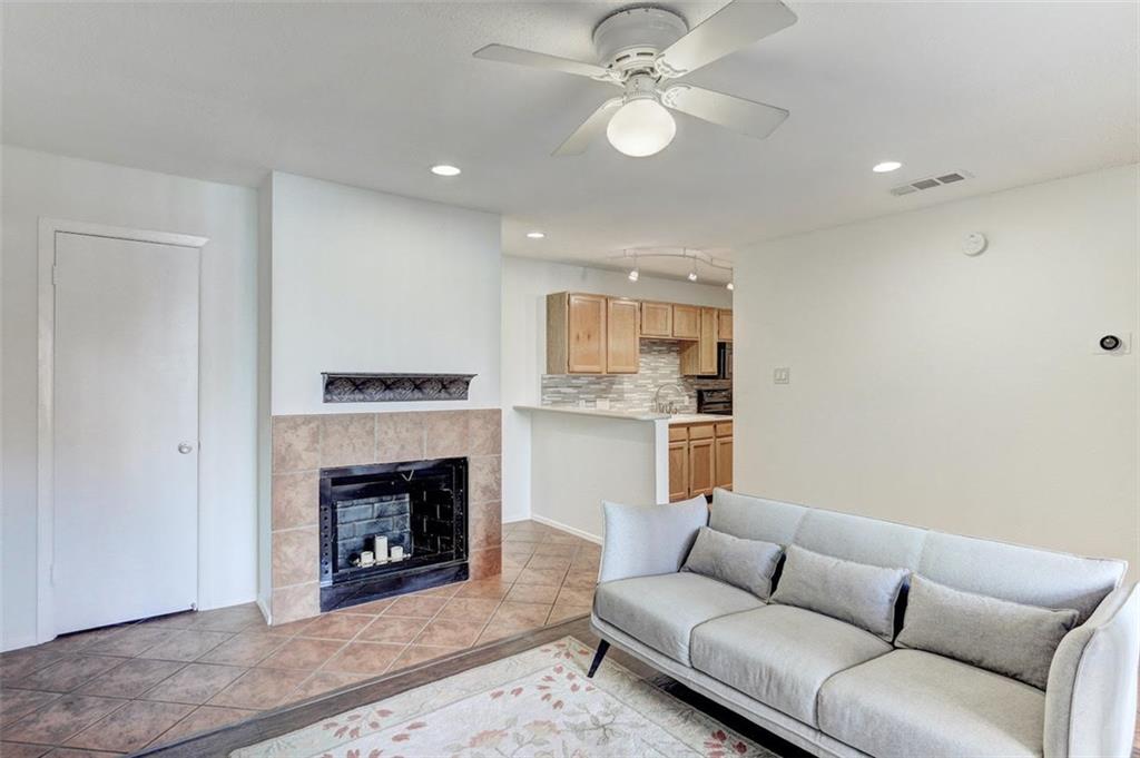 3115 Helms Street, Unit 204 Austin, TX 78705 - Photo 2 of 13 A cozy living space features a tiled fireplace, inviting warmth and connection to the adjacent kitchen.
