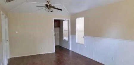 an empty room with wooden floor ceiling fan and windows