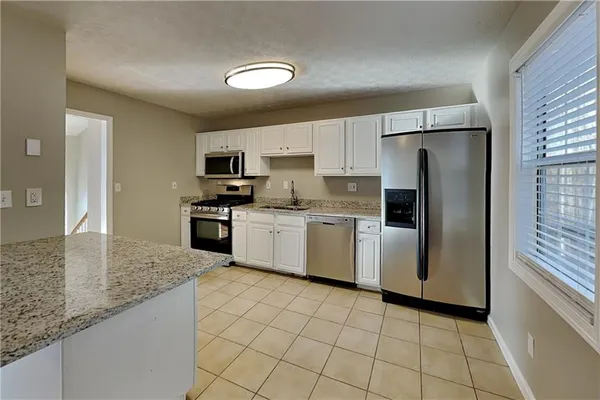 a kitchen with a sink a refrigerator a microwave and cabinets
