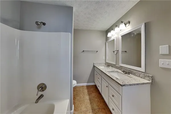 a spacious bathroom with a granite countertop double vanity sink and a mirror