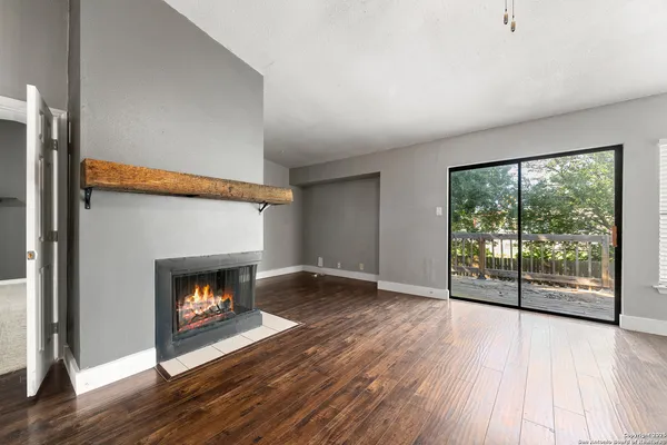 a view of an empty room with wooden floor and a fireplace