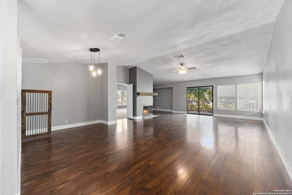 a view of empty room with wooden floor and fan