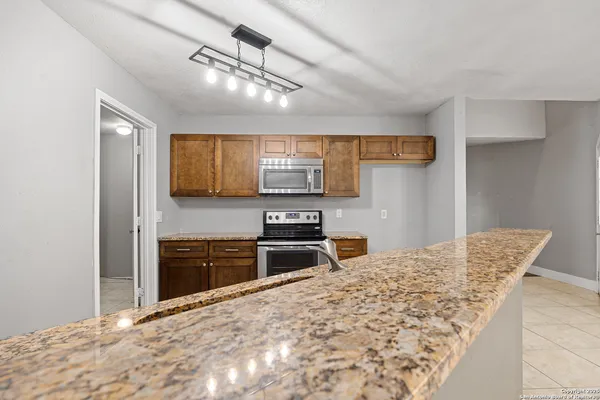 a kitchen with stainless steel appliances granite countertop a stove top oven a sink and a refrigerator