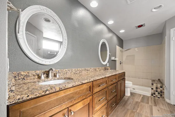 a bathroom with a granite countertop double vanity sink and a mirror