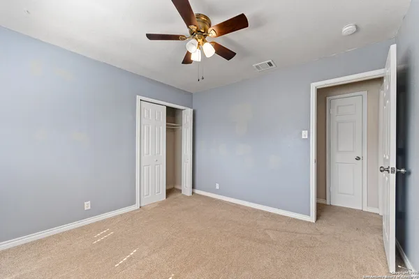 an empty room with closet and a ceiling fan