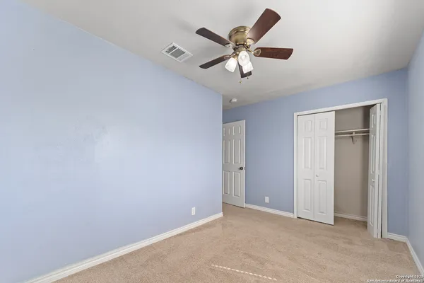 an empty room with a chandelier fan and windows