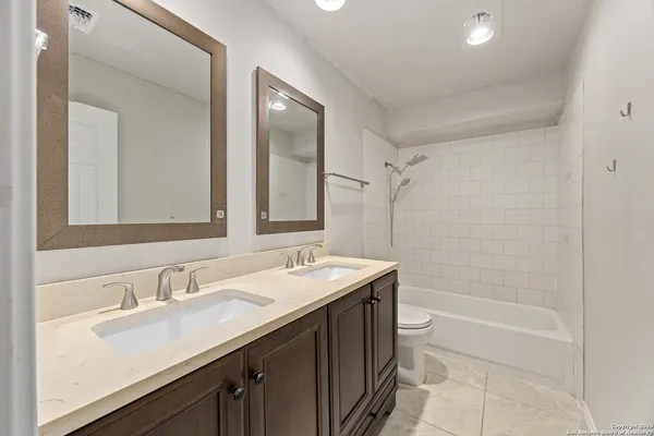 a bathroom with a sink double vanity granite tub shower and a mirror