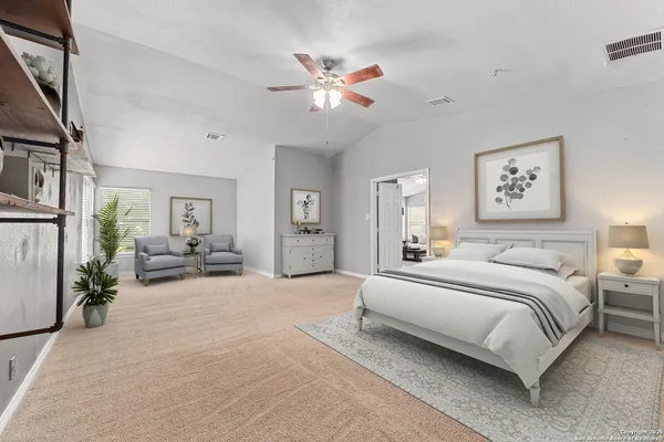 a spacious bedroom with a large bed and a chandelier