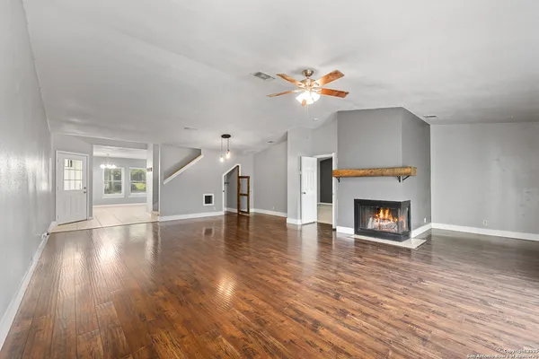 an empty room with wooden floor fireplace and windows