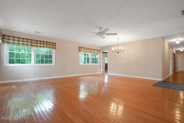 a view of an empty room with window and wooden floor