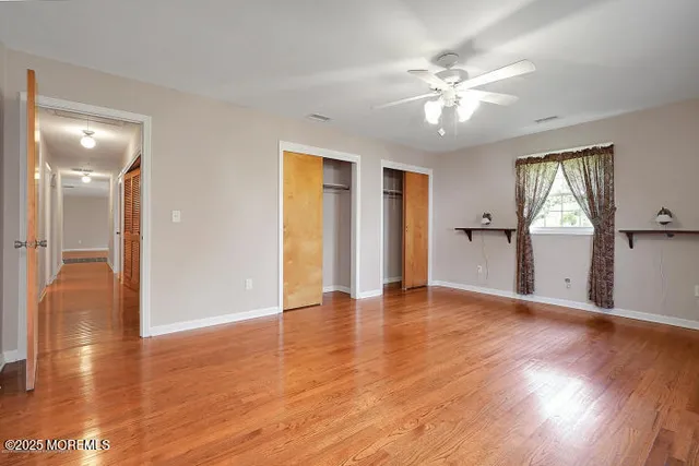 a view of an empty room with window and wooden floor