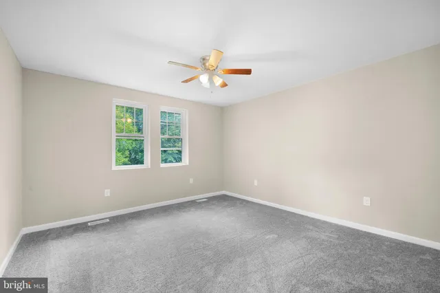 an empty room with windows and chandelier fan