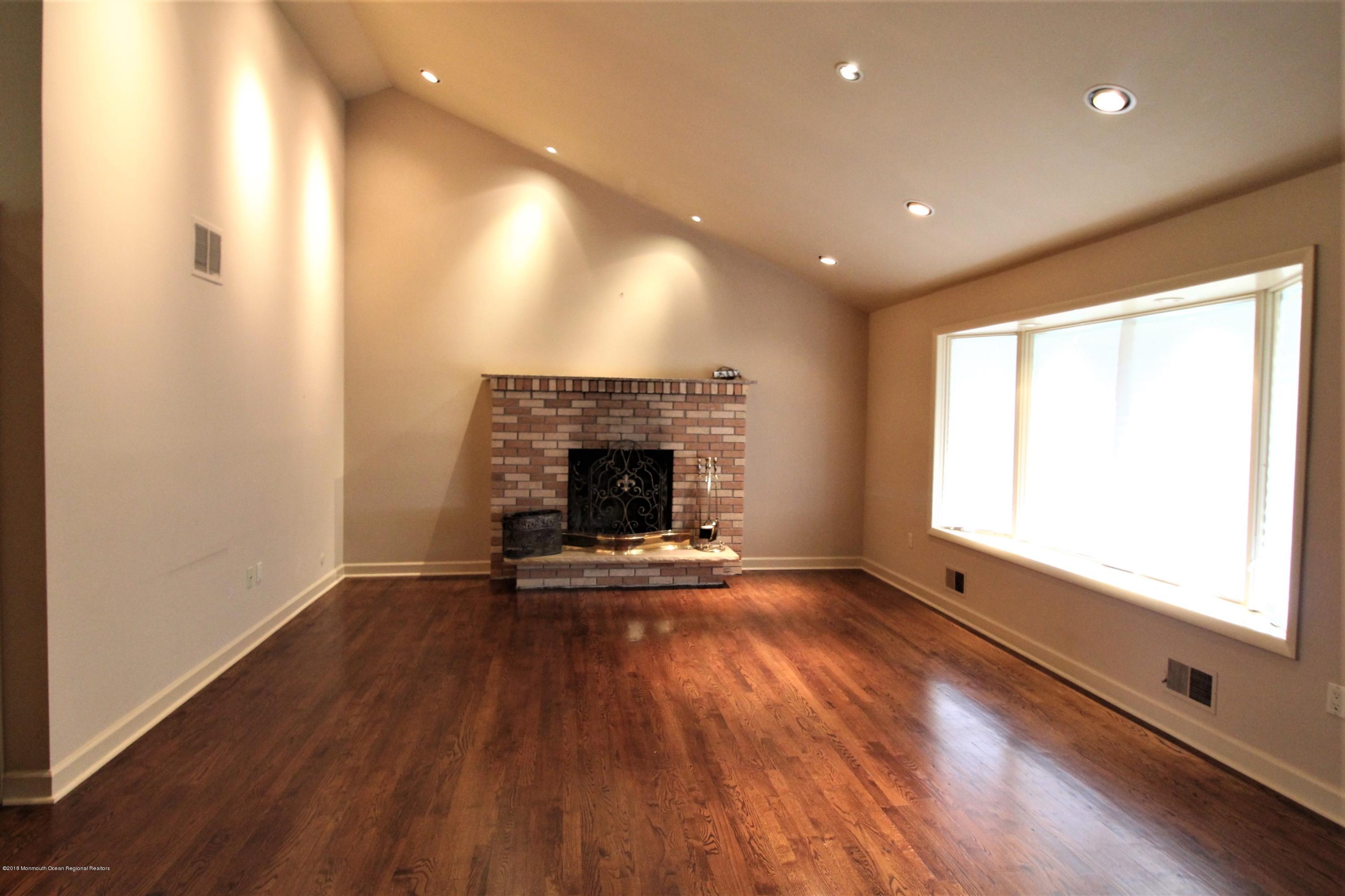 134 Conover Road Morganville, NJ 07751 - Photo 2 of 24 an empty room with wooden floor and fireplace