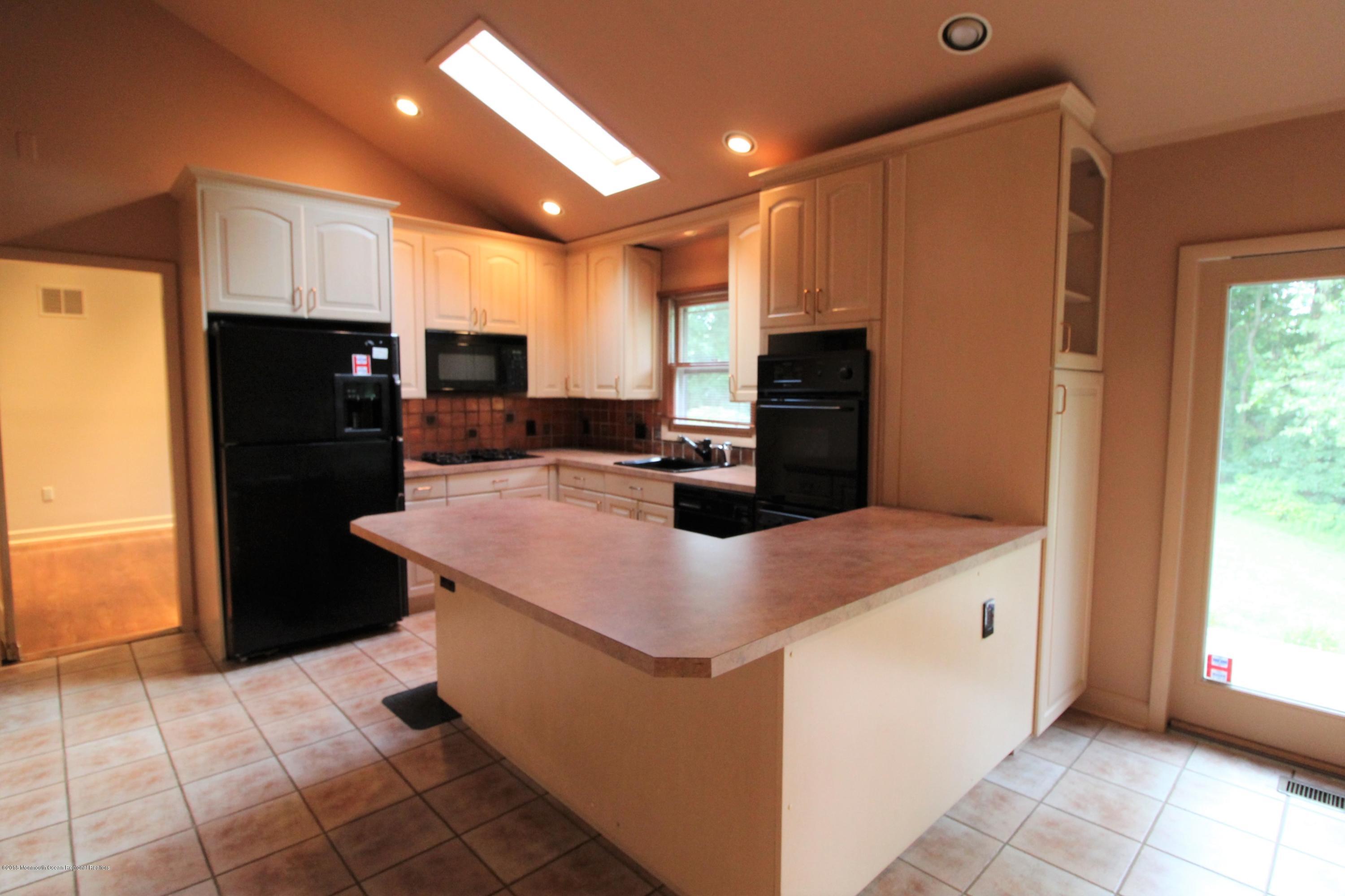 134 Conover Road Morganville, NJ 07751 - Photo 4 of 24 a kitchen with kitchen island a counter top space cabinets and a refrigerator