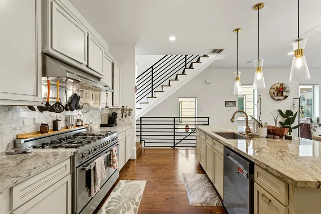 a kitchen with stainless steel appliances granite countertop a sink a stove and a wooden floors