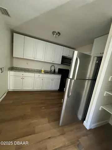 a kitchen with stainless steel appliances granite countertop a refrigerator a stove and a sink with wooden floor