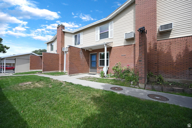 285 West 600 North, Unit 2 Logan, UT 84321 - Photo 19 of 21 Exterior brick and siding facade featuring a front entrance, a window with shutters, and an adjacent carport structure