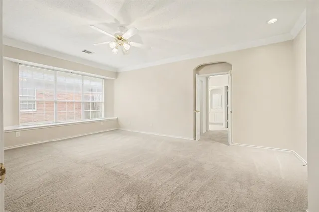an empty room with windows and ceiling fan