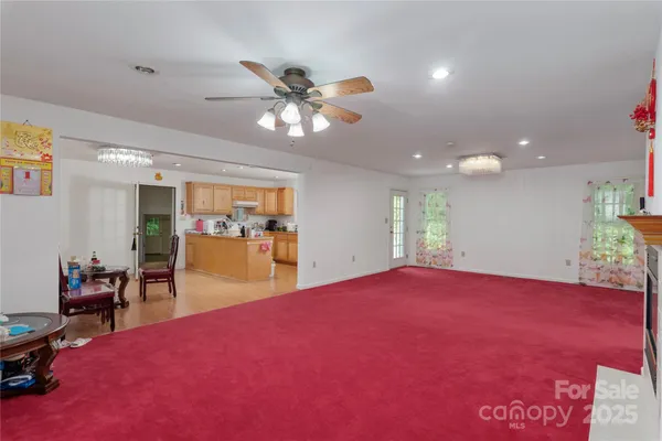 a view of an empty room with window and a kitchen