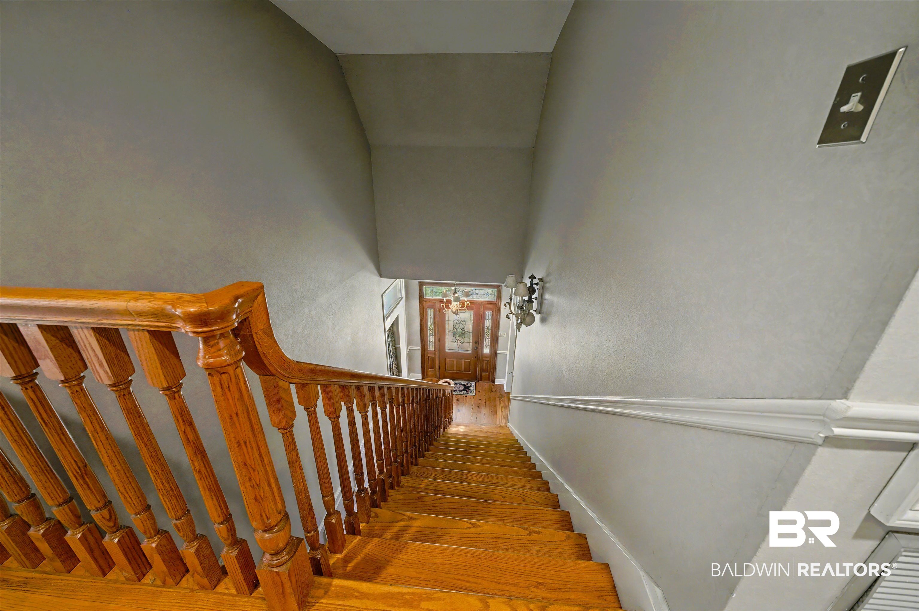 15810 County Road 73 Foley, AL 36535 - Photo 41 of 56 Staircase featuring hardwood / wood-style flooring, a towering ceiling, and a chandelier
