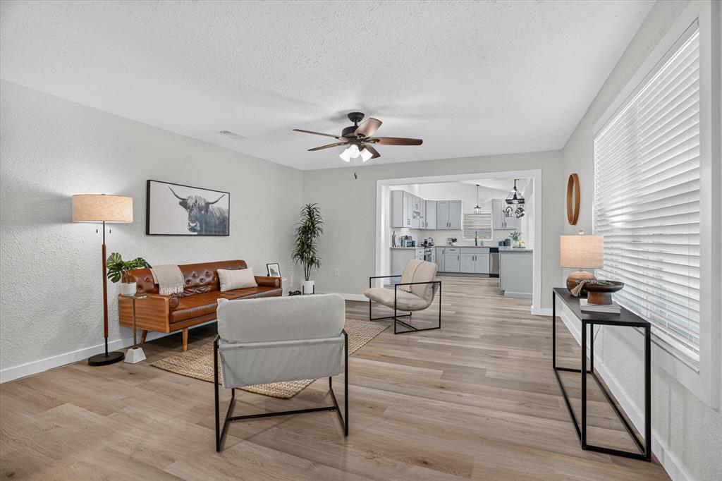795 Meadow Road Springtown, TX 76082 - Photo 3 of 25 Wood-finish flooring throughout, ceiling fan with light fixture, ample natural light from multiple windows, and a clear architectural opening to the kitchen