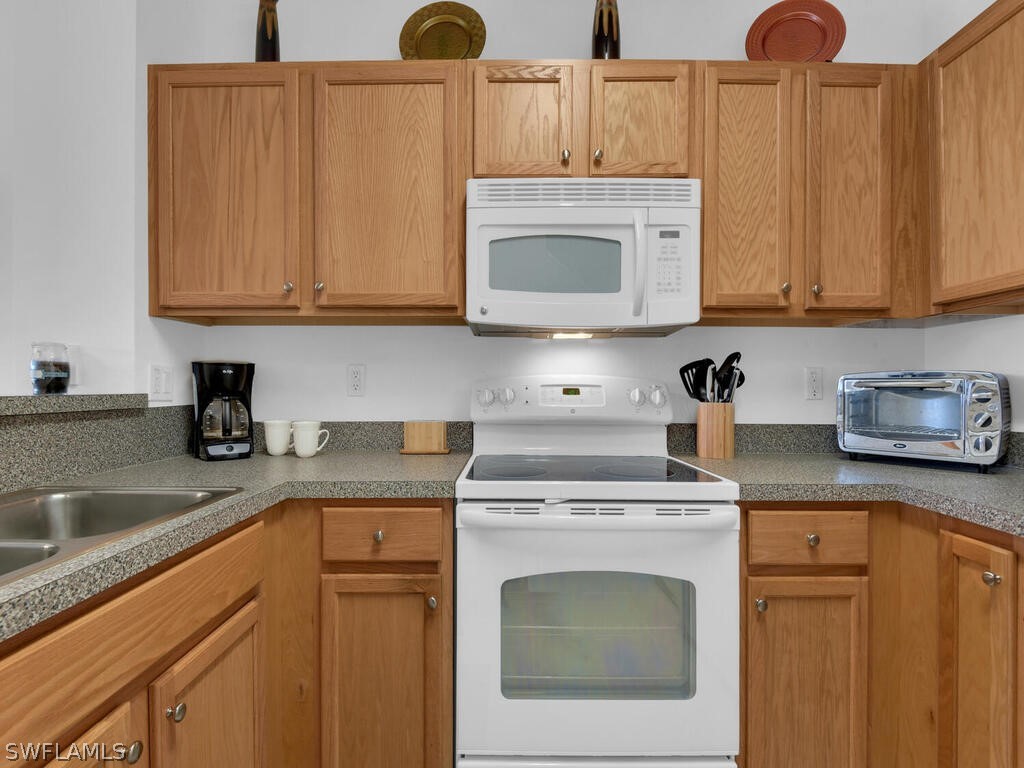 11740 Eros Road Lehigh Acres, FL 33971 - Photo 8 of 30 a kitchen with granite countertop wood cabinets and white appliances