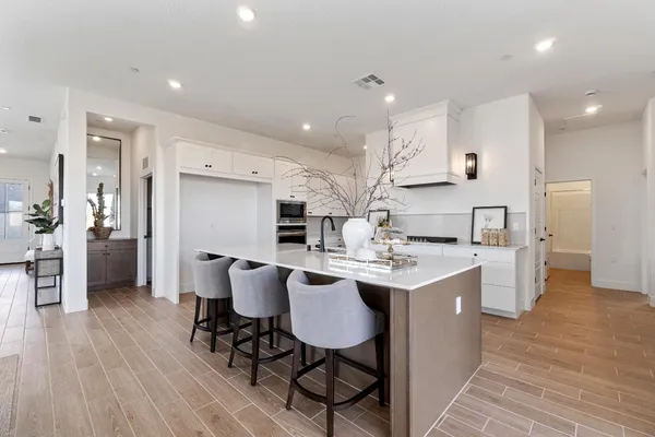 a kitchen with stainless steel appliances a dining table chairs stove refrigerator and cabinets