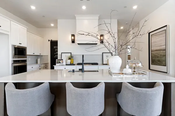 a kitchen with stainless steel appliances granite countertop a sink a microwave and chairs