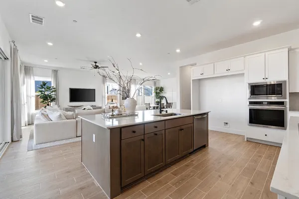 a large kitchen with stainless steel appliances a large counter top a sink and a refrigerator