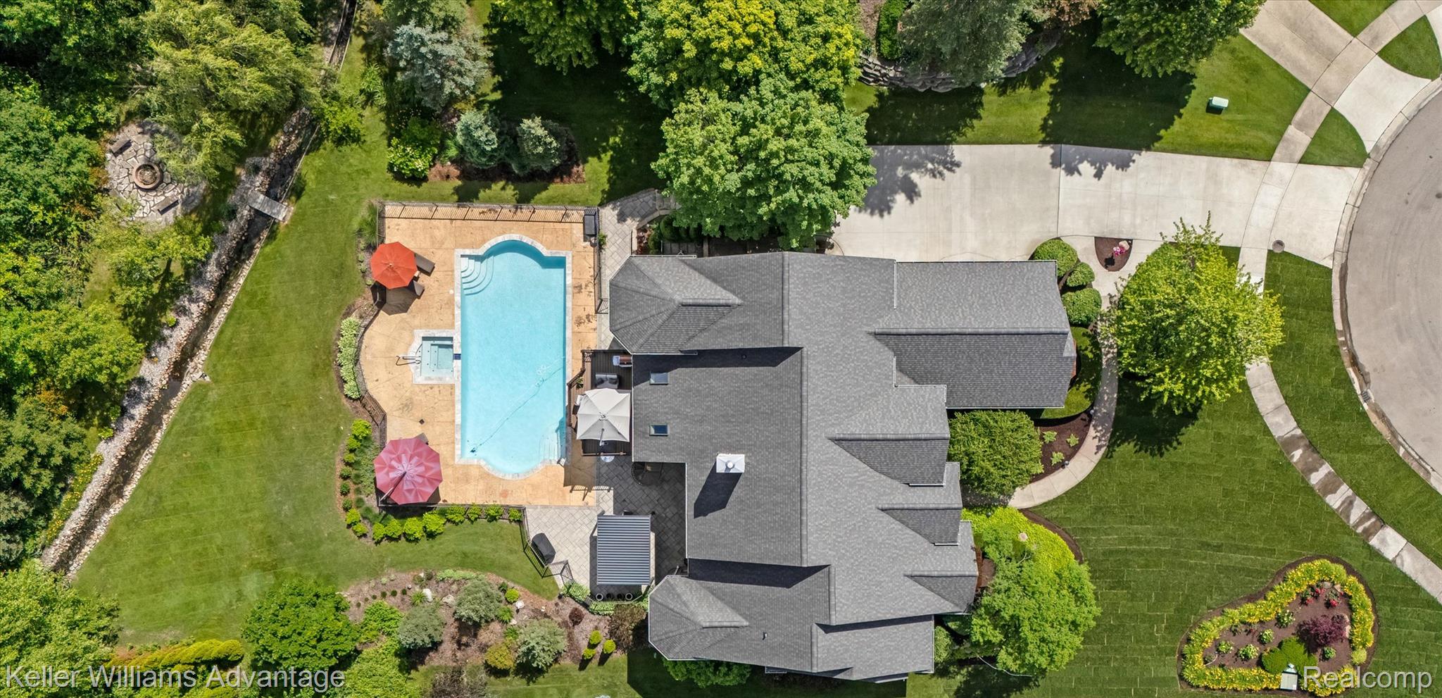 22878 Tree Top Court South Lyon, MI 48178 - Photo 59 of 75 Expansive property featuring a large swimming pool with an integrated spa, extensive hardscaping, and surrounding green space