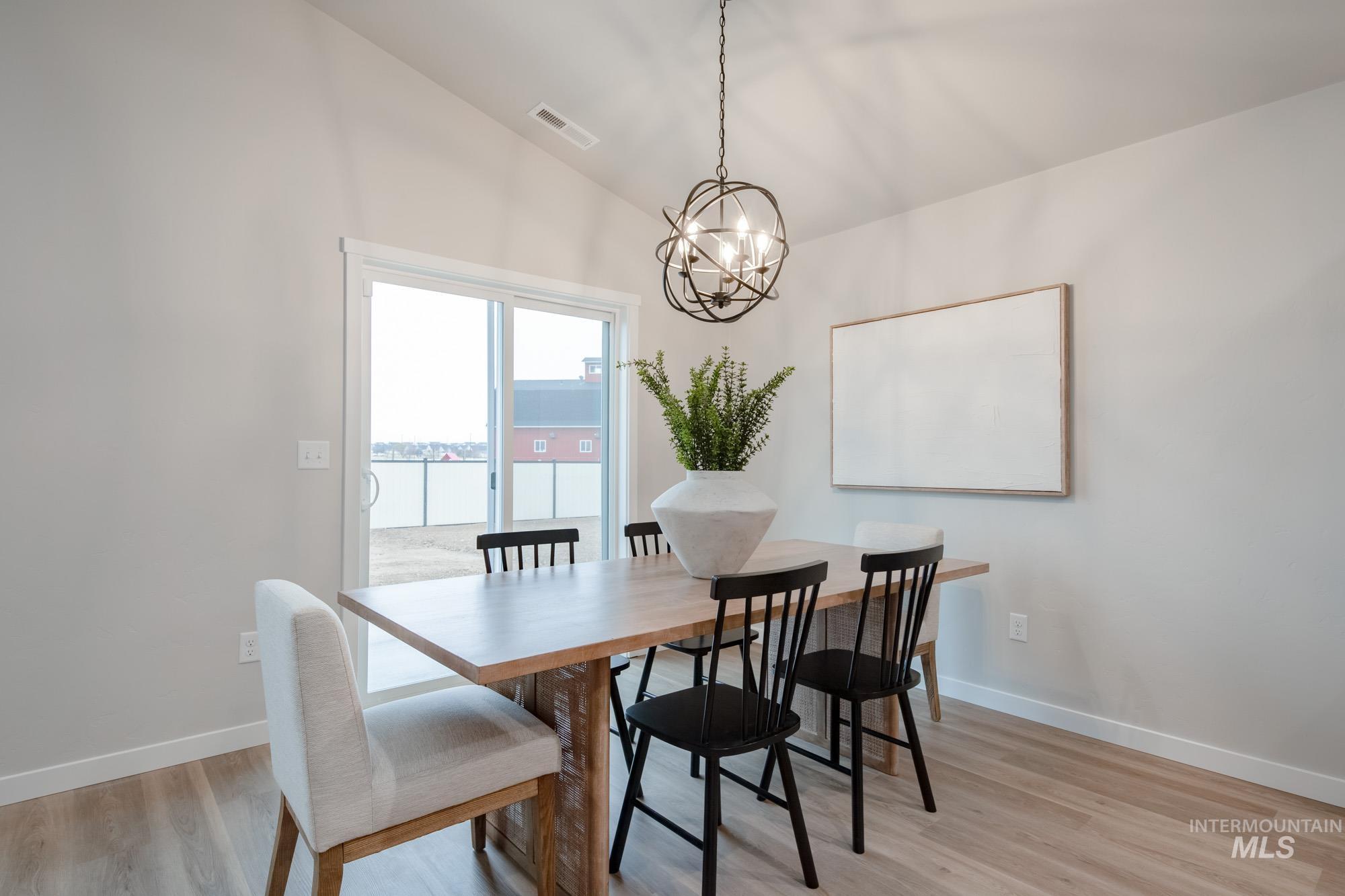 1760 West Unforgettable Street Meridian, ID 83642 - Photo 11 of 26 Dining room with vaulted ceiling, light wood-style floors, a water view, and a chandelier
