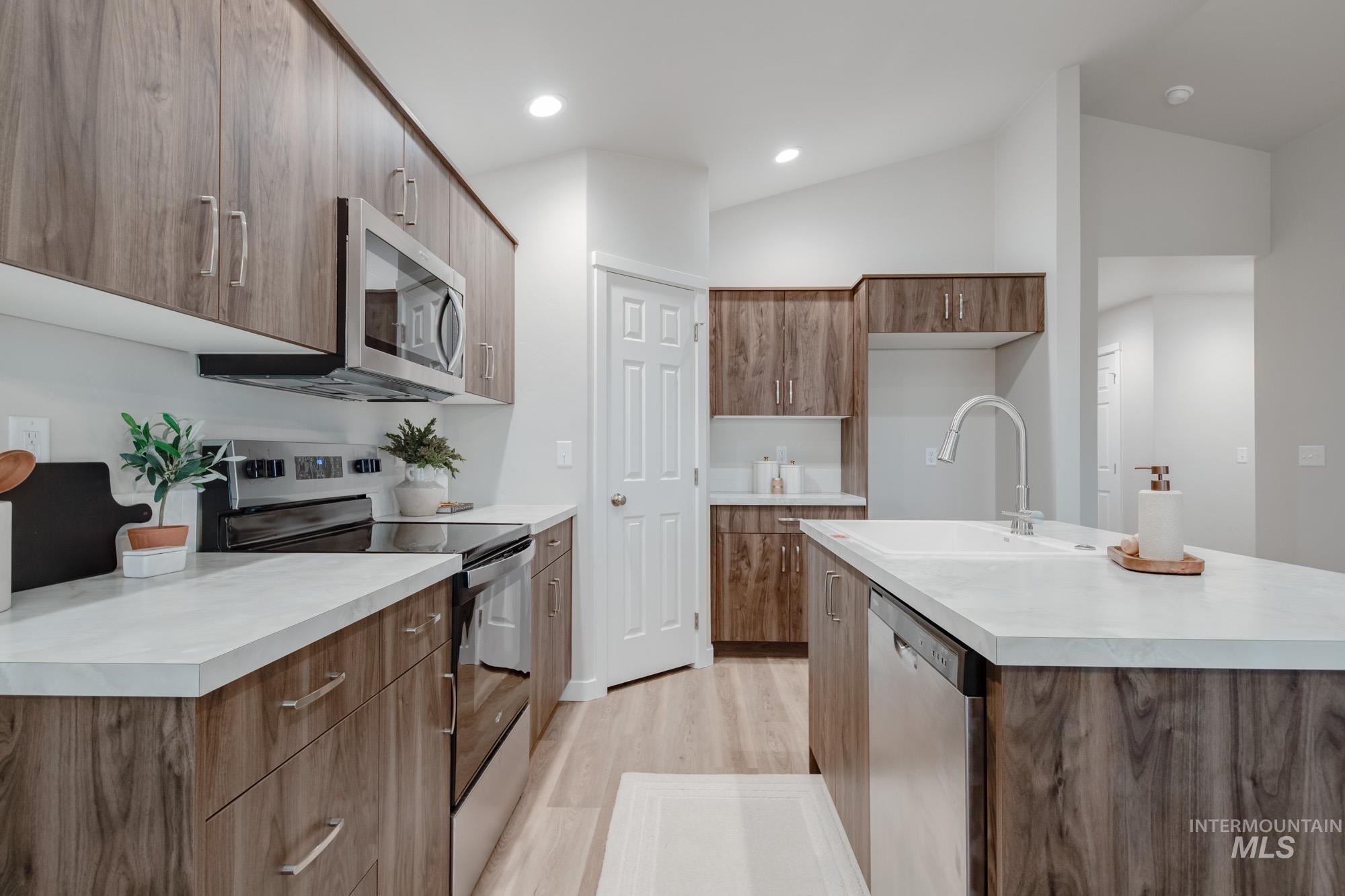 1760 West Unforgettable Street Meridian, ID 83642 - Photo 12 of 26 Kitchen with stainless steel appliances, light countertops, modern cabinets, brown cabinets, and light wood finished floors