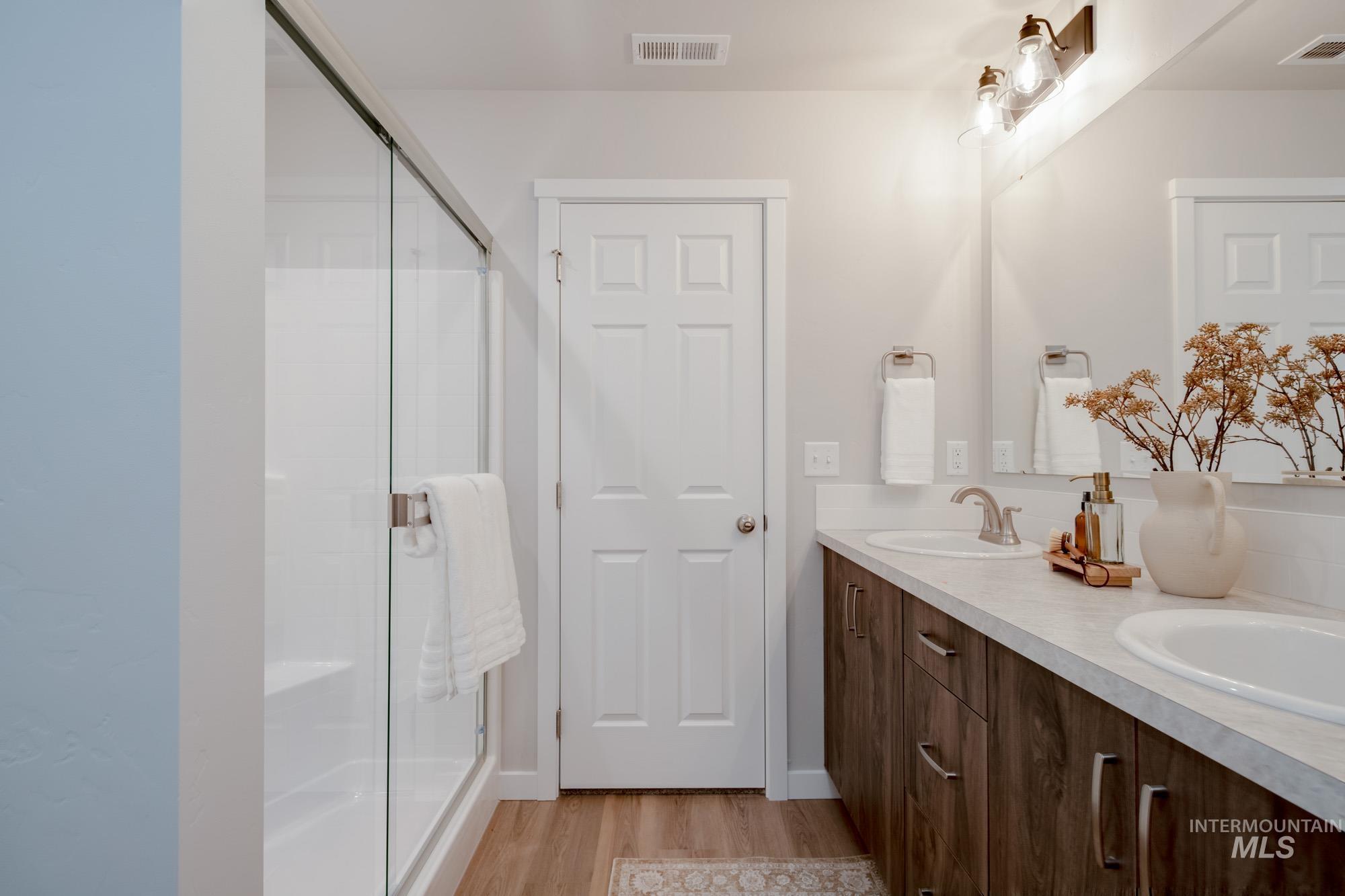 1760 West Unforgettable Street Meridian, ID 83642 - Photo 22 of 26 Full bathroom featuring double vanity, light wood finished floors, and a shower stall