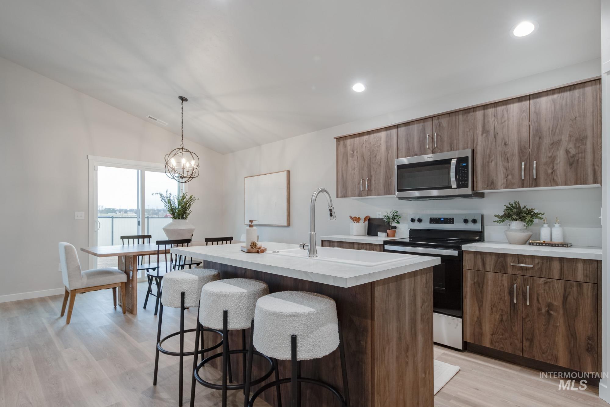 1760 West Unforgettable Street Meridian, ID 83642 - Photo 9 of 26 Kitchen featuring stainless steel appliances, a center island with sink, pendant lighting, vaulted ceiling, and a breakfast bar